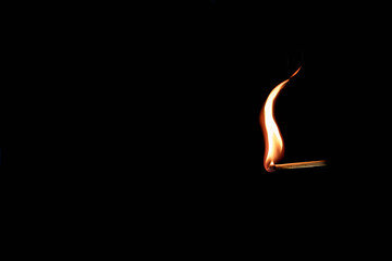 Single match stick burning a clean orange flame. Isolated on black background.