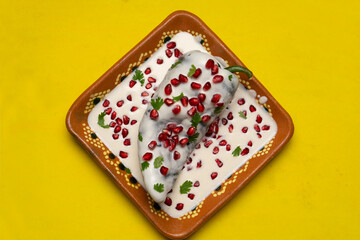 Fototapeta premium Mexican stuffed poblano peppers also called nogada with pomegranate on yellow background