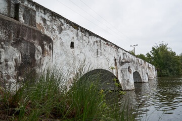 Old ruined historic road bridge over middle ages pond or water reservoir in southern Bohemia, beautifull and pitoresque region in Czech Republic, popular for hiking or cycling during summer holidays.