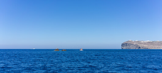 Orange and white fishing boat followed by seagulls on aegean sea. blue sky and sunny day