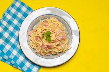 creamy spaghetti pasta with ham on yellow background