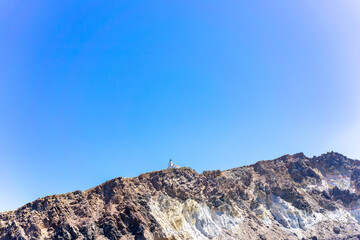 Cliff and lighthouse on the southern of Thira island in Greek Islands on a clear, sunny day with bright, blue sky. Akrotiri, Santorini, Greece. Akrotiri