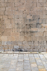 Exterior detail of an old Mediterranean historic building, stone wall facade and street.