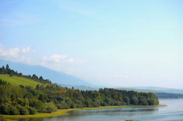 Autumn landscape of a lake shore with colorful trees and blue mountains in the background