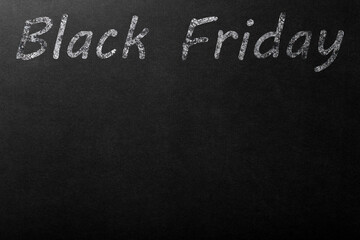 Fototapeta premium The inscription Black Friday in white chalk on a dark blackboard. Copyspace on a black background.
