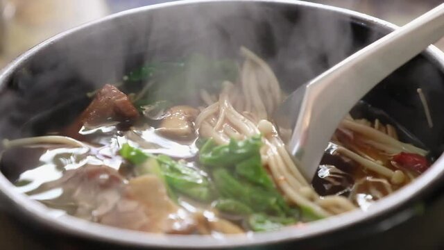 close up of tasty yummy delicious Asian food hot herbal soup call "Bak kut teh soup" with smoke , pork rib dish cooked in broth popularly served in Thailand