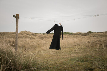 Black dress hanging on washing line in field