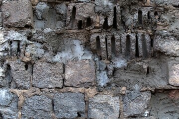 fragment of an ancient stone wall built of various types of stone and concrete