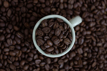 Coffee beans in brown coffee cup and coffee beans in the background