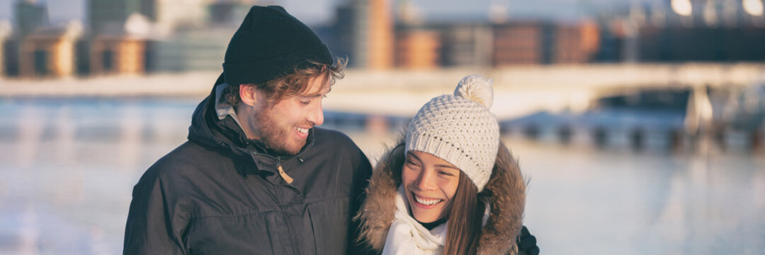 Happy young couple walking outside in cold weather. City winter lifestyle panoramic banner. Asian woman and Caucasian man interracial relationship.