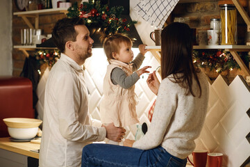 a young family spends time in the kitchen, mom and dad are playing with their daughter
