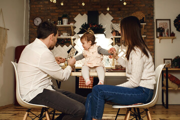 Dad mom and daughter have dinner in the kitchen, the child sits at the table and communicates with the parents