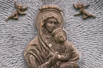 Fototapeta na wymiar Virgin Maria with child on vintage bas-relief. Face mother with baby.