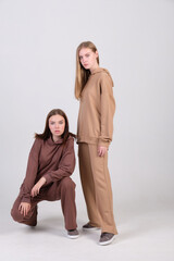 Pair of fashionable models posing in studio in brown and beige casual suits for clothing catalog. Examples of autumn female fashion.