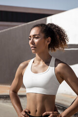 Fototapeta na wymiar Portrait of a sweat afro fitness girl resting after workout, at park, with white top