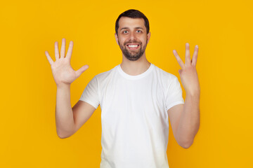 Fototapeta premium Modern young man with a beard in a white tank top shows number eight with fingers on hand, smiling confidently and happily, looking into the camera. The man shows eight fingers. Number 8