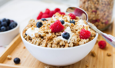 bowl of fresh muesili cereals with curd yogurt and berries on the breakfast table. blurry background for text area.