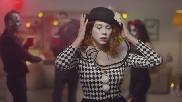 Portrait of beautiful young woman in clown halloween costume posing for camera at house party