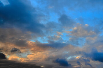 Naklejka na ściany i meble blue twilight sky covered by orange shaded clouds covering the horizon.
