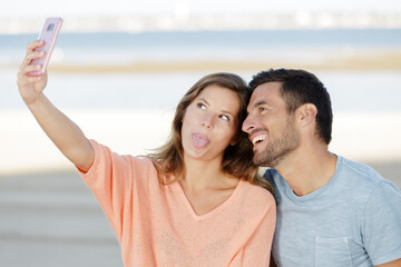 couple taking selfie with a phone and making silly faces