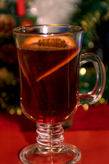 Winter drink. Mulled wine with cherries in a beautiful mug on a red background.