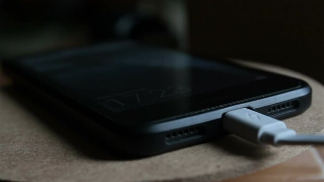 Close up of smartphone charging battery. Black smartphone is being charged from charger.