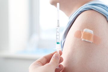 Vaccination of man, adult in doctor's office. Beige adhesive plaster,tape gauze napkin.Syringe with vaccine for covid-19 coronavirus,flu,infectious diseases. njection.Clinical trials for human,child