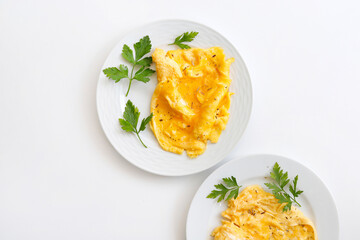 Scrambled eggs on plate over white background. Top view, flat lay