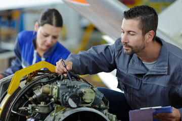 apprentice studying car engines with a mechanic