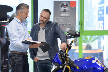 Salesman informing client about motorcycle - obrazy, fototapety, plakaty