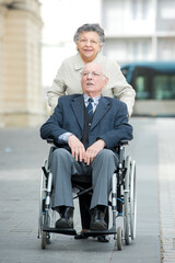 senior woman pushing man in wheelchair