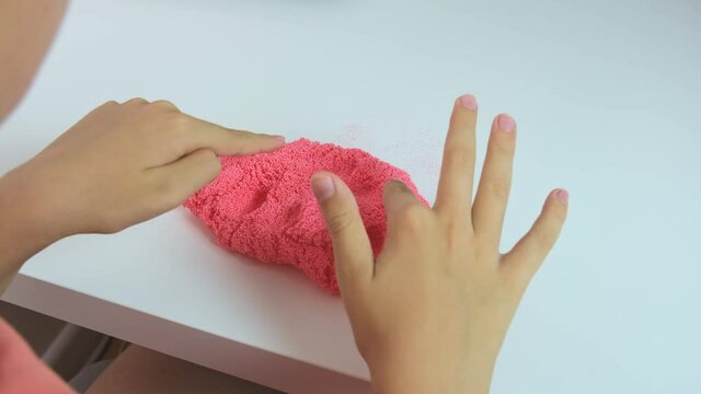 A boy playing with slime, crushing squizing and crumpling pink plasticine, gum for hands with small balls inside, anti stress and relaxing game, close up
