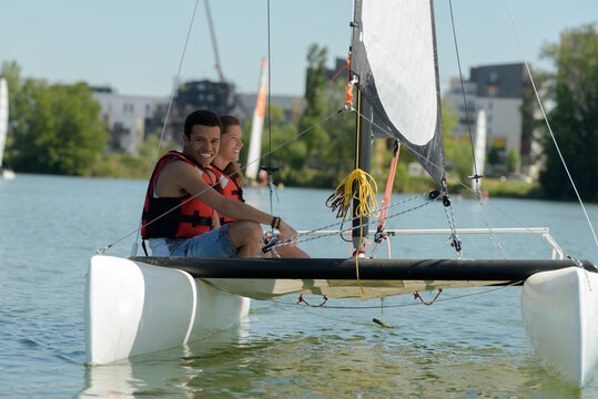 Young Adults On Board Small Catamaran Sailboat