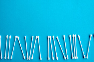 Cotton ear swabs sticks on blue background. close up. Image with selective focus, noise effect and toning. Top view. Flat lay.