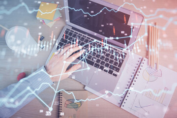 Double exposure of man's hands typing over computer keyboard and forex graph hologram drawing. Top view. Financial markets concept.