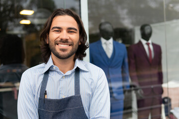 Portrait of brazilian business man with big smile looking at camera in front of store facade....