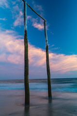 wooden poles on the beach at sunset glow