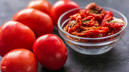 Dried tomatoes with garlic and olive oil in a bowl on a gray table background