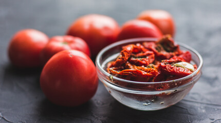 Dried tomatoes with garlic and olive oil in a bowl on a gray table background