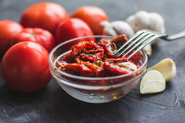 Dried tomatoes with garlic and olive oil in a bowl on a gray table background