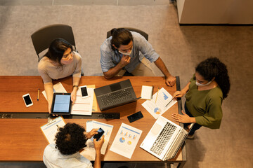 Focused latin business team with face mask having a meeting in open office space. Communication, workspace, meeting concept..