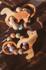 Cute wooden baby toys on the marble background. Animal toys. Eco accessories, beanbag and teethers for newborn. Flat lay, top view