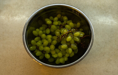 Green grapes in the kitchen in a metal bowl