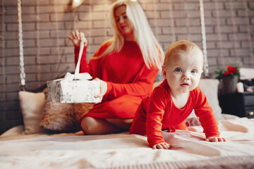 Fototapeta premium Beautiful mother in a red dress. Family with cristmas gifts. Little boy on a bed