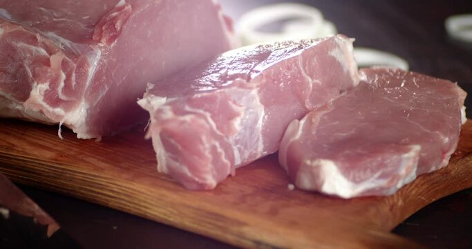 Sliced chunks of raw pork escalope slowly rotate. 