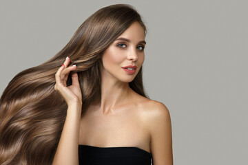 Fashion woman with wavy hair on gray background. Hair touch. copycpase