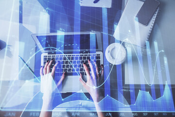 Double exposure of woman hands working on computer and forex chart hologram drawing. Top View. Financial analysis concept.