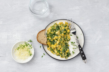 Scrambled eggs with kale and cheese on a light gray background, top view. delicious homemade...