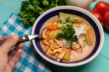 Mexican chicken soup with vegetables and rice on turquoise background