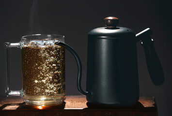 A teapot with a thin spout and a glass mug with hot tea